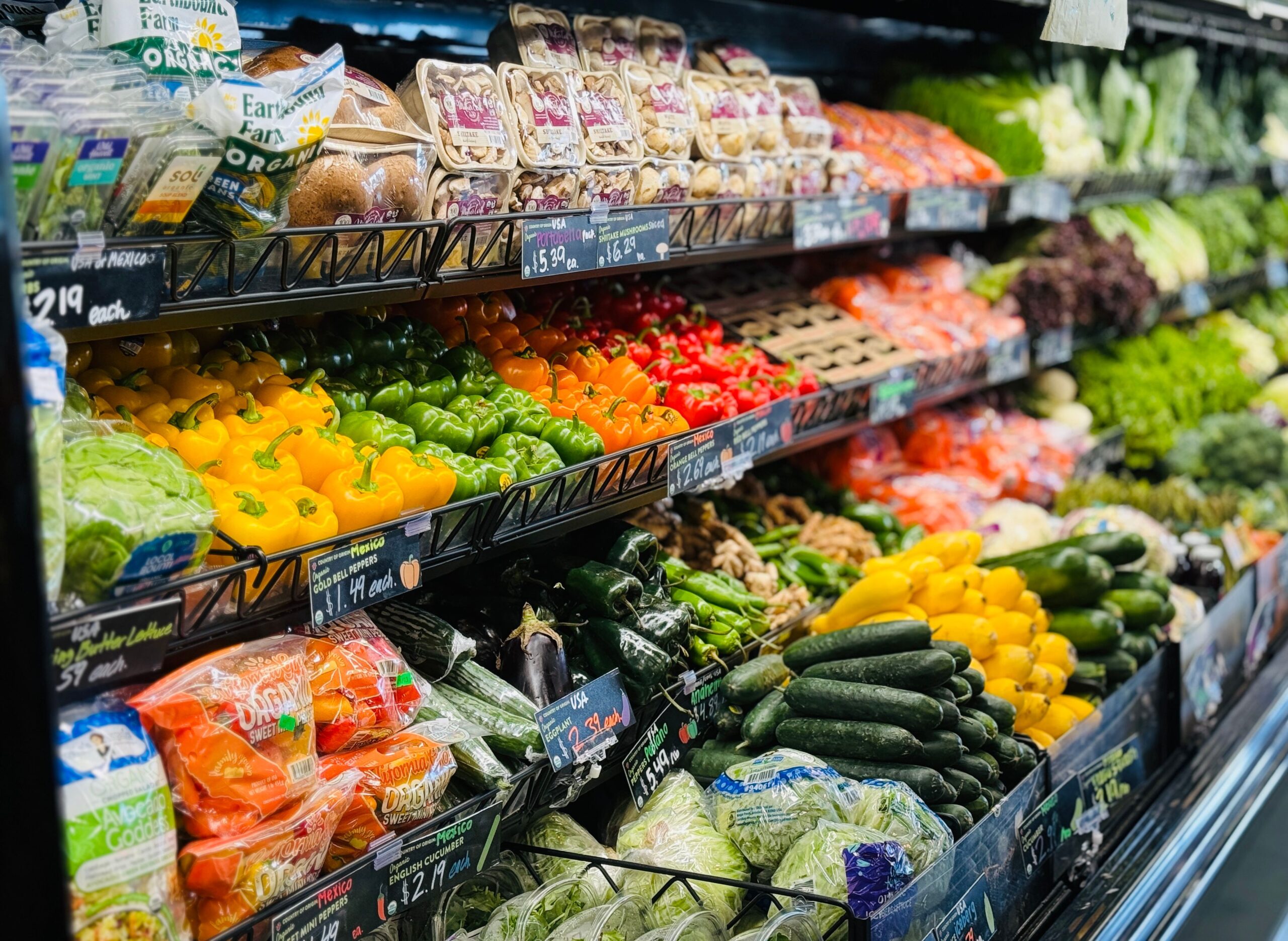 Mostrador de fruta y verdura expuestos ordenadamente en un supermercado.